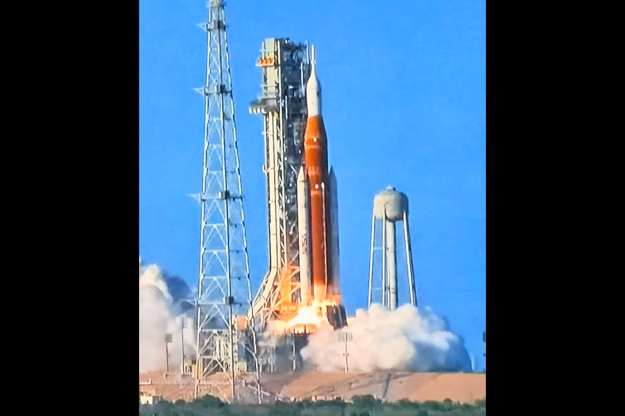 The Artemis II SLS rocket climbing off the pad on a column of fire