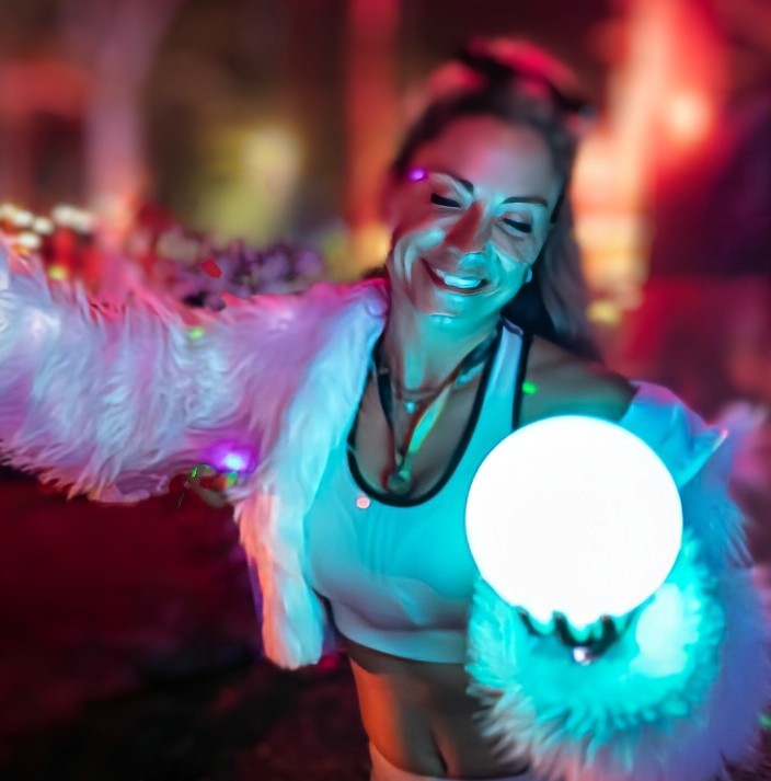 A performer with a glowing orb under festival lights at night