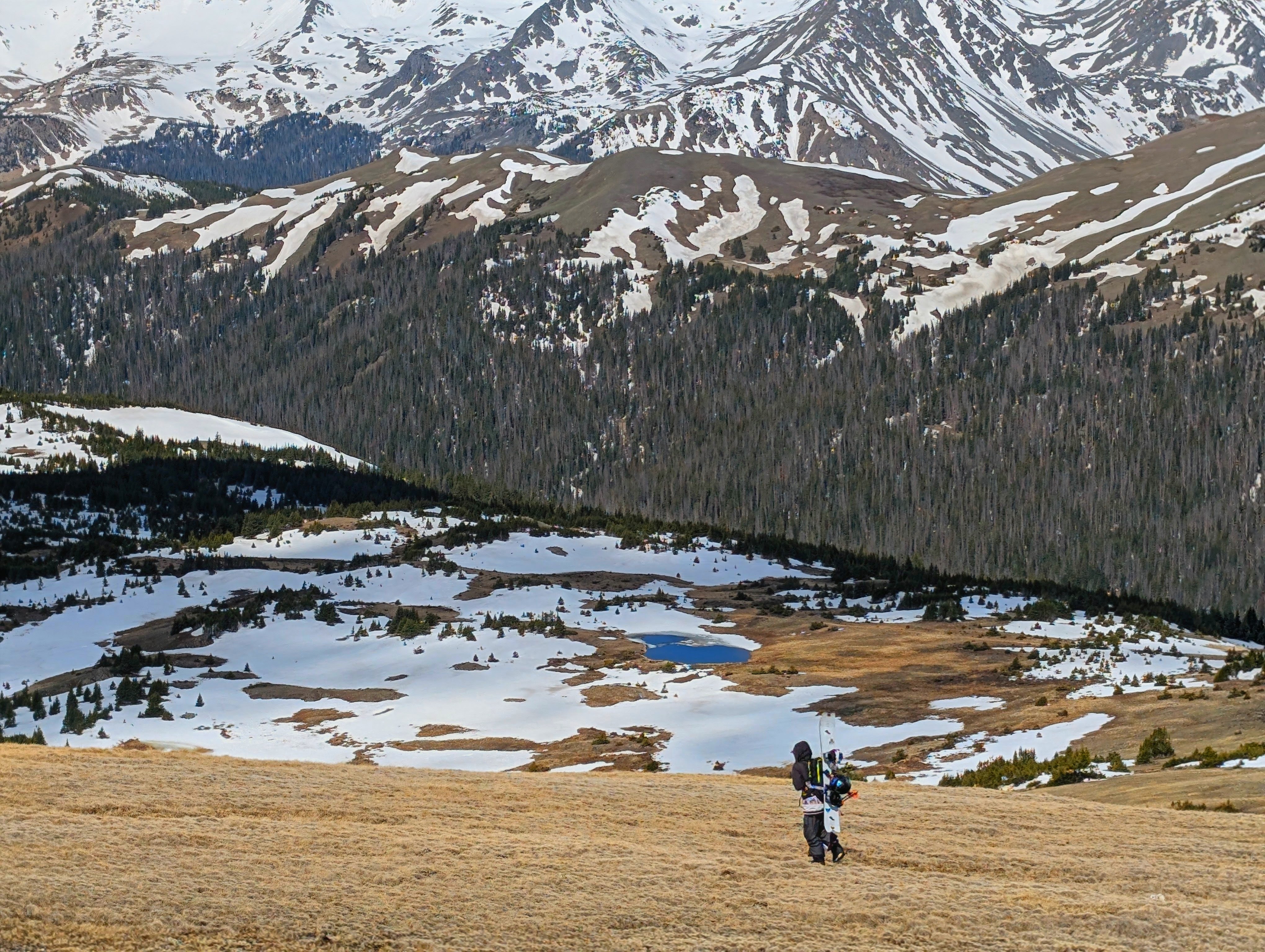 A snowboarder on lingering snow along the Alpine Ridge Trail