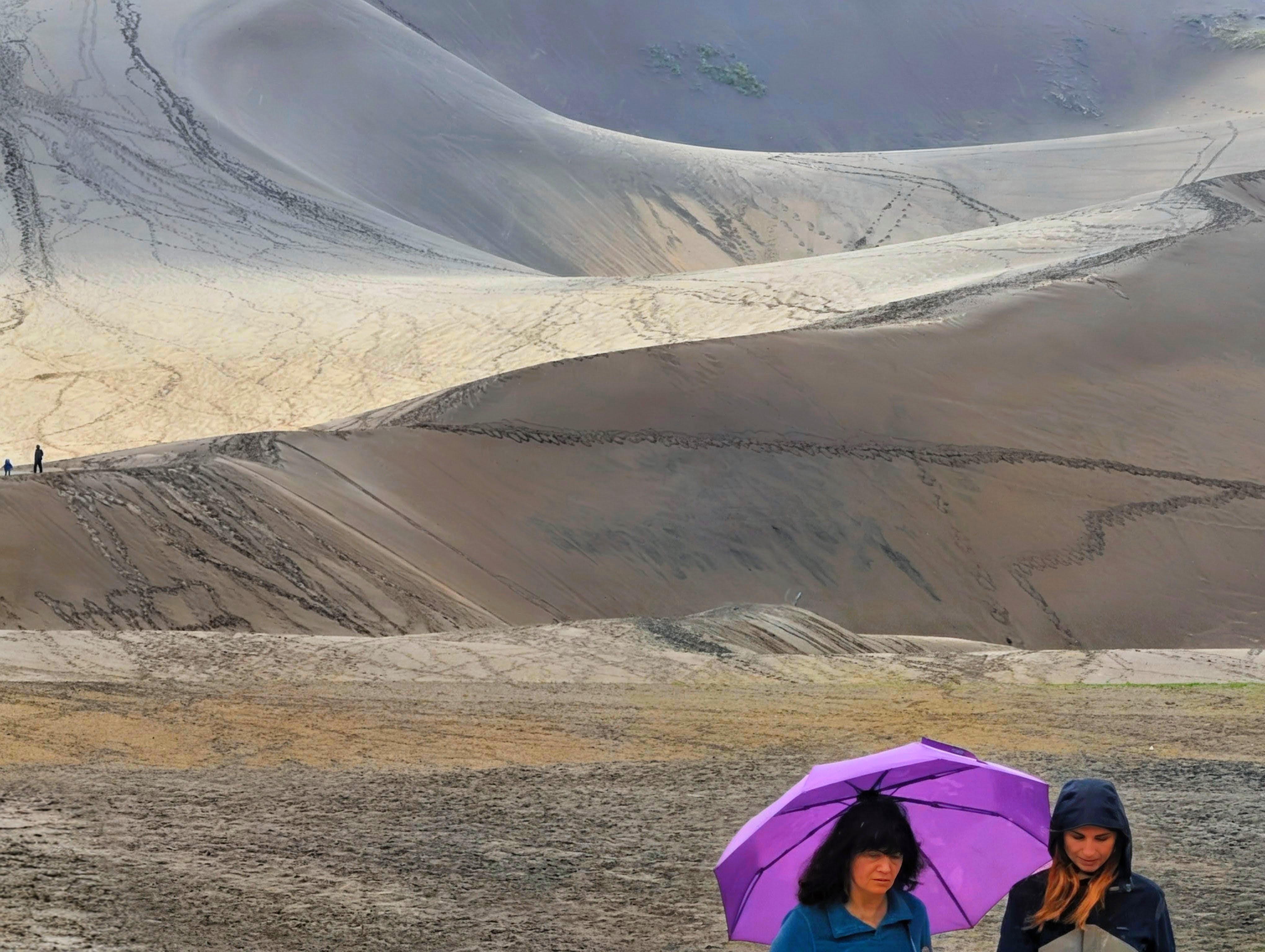 Two people with a purple umbrella beneath the Great Sand Dunes
