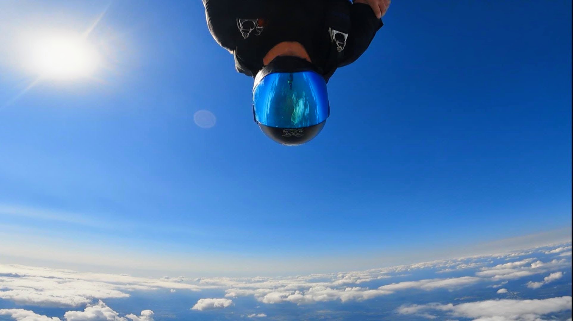 A head-down freeflyer against the sun with a cloud deck below